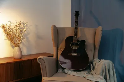 Akustična gitara u fotelji u toploj sobi